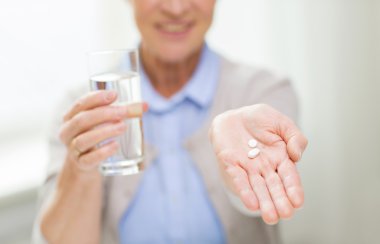 close up of senior woman with water and pills clipart