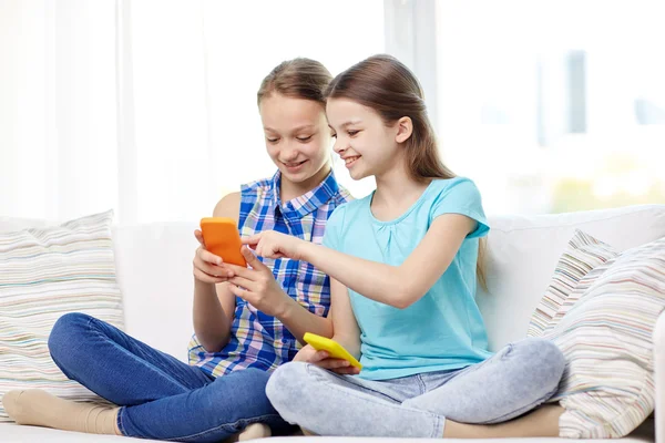 Happy girls with smartphones sitting on sofa — Stock Photo, Image