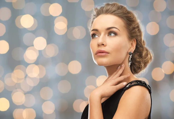 Beautiful woman wearing earrings over lights — Stock Photo, Image