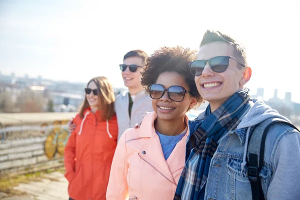 Happy teenage friends in shades hugging on street — Stock Photo, Image