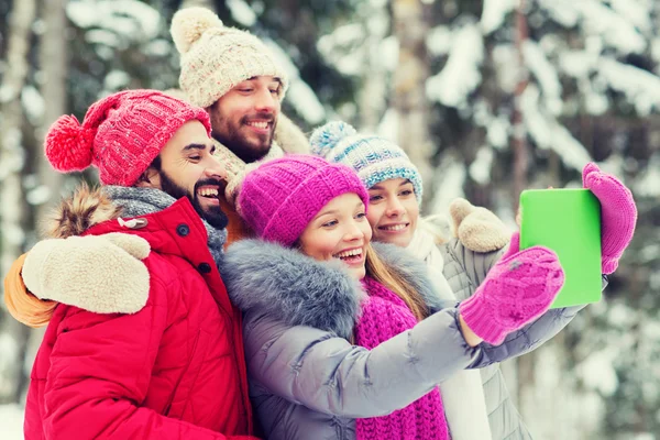 Smiling friends with tablet pc in winter forest — Stock Photo, Image