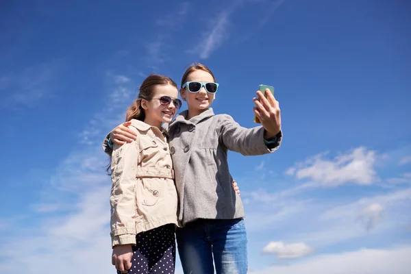 Meninas felizes com smartphone tirando selfie ao ar livre — Fotografia de Stock