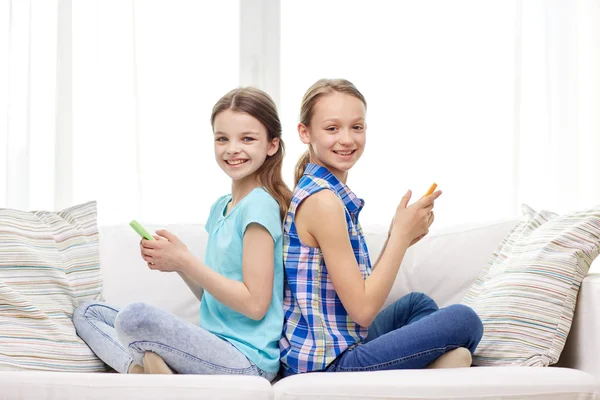 Chicas felices con teléfonos inteligentes sentados en el sofá — Foto de Stock