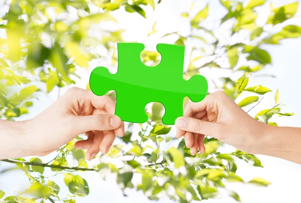 Mani con puzzle verde su sfondo naturale — Foto Stock