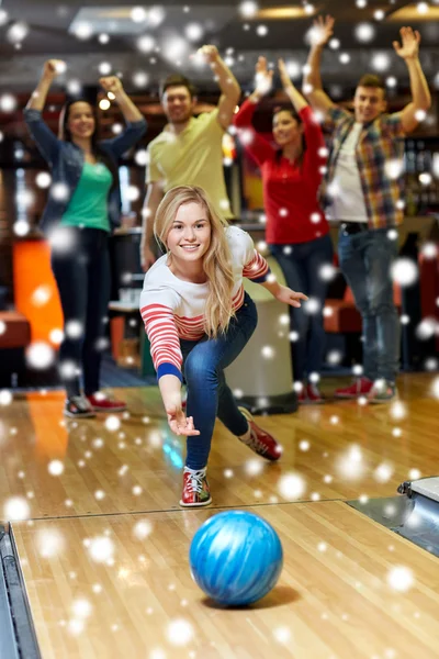 Happy young woman throwing ball in bowling club — Stock Photo, Image