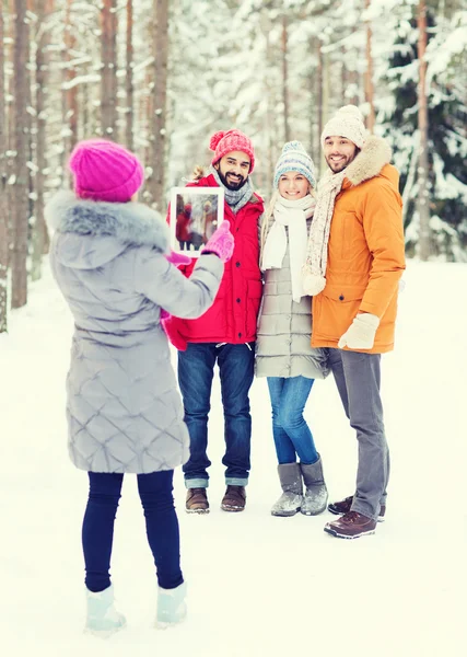 Улыбающиеся друзья с планшетным ПК в зимнем лесу — стоковое фото