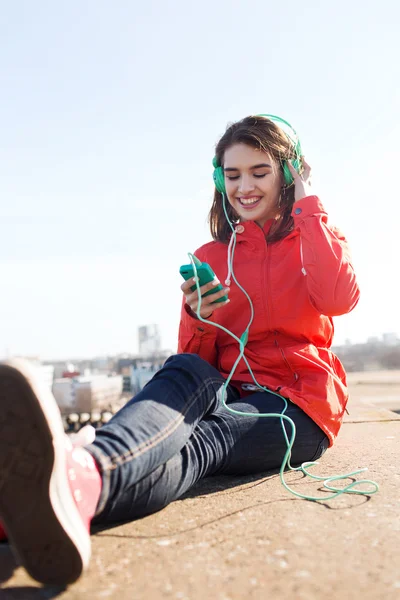 Šťastná mladá žena s smartphone a sluchátka — Stock fotografie