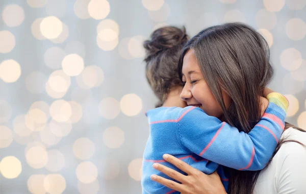 Happy mother and daughter hugging over lights — Stockfoto