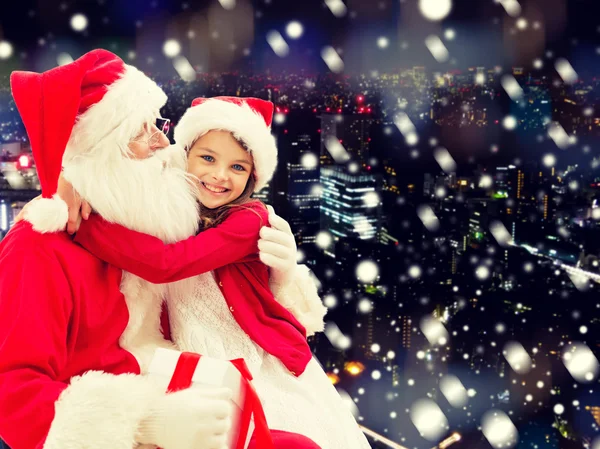 Lächelndes kleines Mädchen mit Weihnachtsmann und Geschenken — Stockfoto