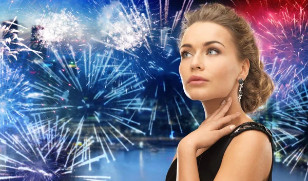Beautiful woman wearing earrings over firework — Stockfoto
