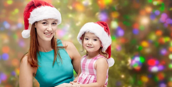 Lycklig mamma och liten flicka i santa hattar — Stockfoto