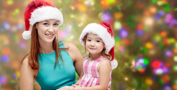 Glückliche Mutter und kleines Mädchen in Weihnachtsmützen — Stockfoto