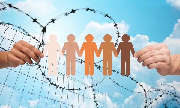 Hands holding people pictogram over barb wire — Φωτογραφία Αρχείου