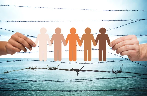 Hands holding people pictogram over barb wire — Stock Photo, Image