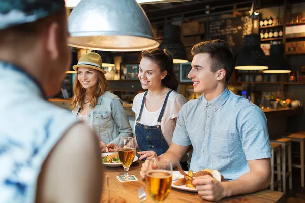 Счастливые друзья едят и пьют в баре или пабе — стоковое фото