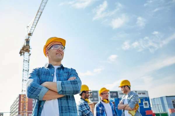 Grupa budowniczych uśmiechający się w hardhats na zewnątrz — Zdjęcie stockowe