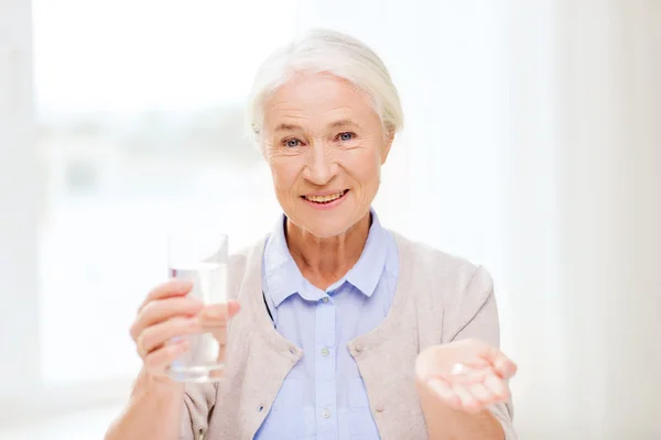 Feliz anciana con agua y medicina en casa —  Fotos de Stock