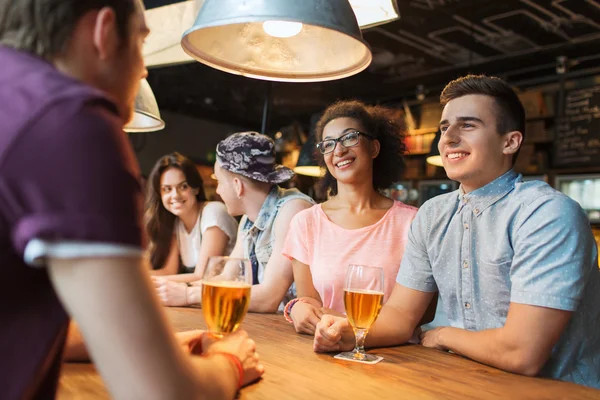 Щасливі друзі п'ють пиво і розмовляють в барі — стокове фото
