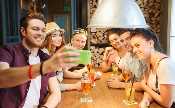 Счастливые друзья со смартфоном делают селфи в баре — стоковое фото
