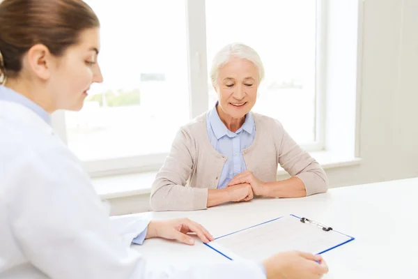 Doctor with clipboard and senior woman at hospital — Stock Photo, Image