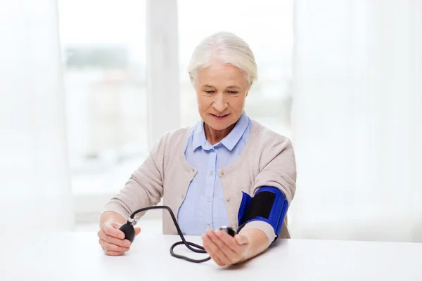 Old woman with tonometer checking blood pressure — Stock Photo, Image