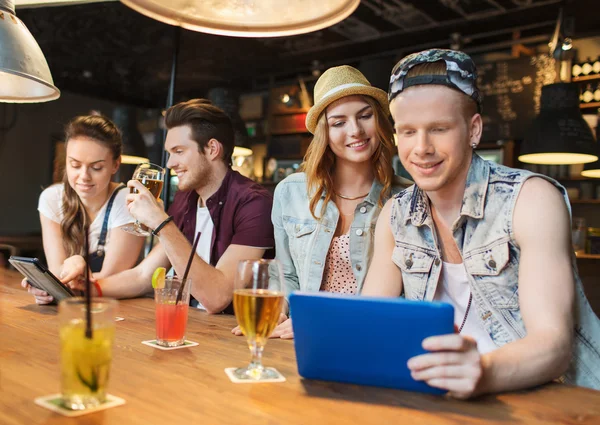 Amigos felices con PC tableta y bebidas en el bar —  Fotos de Stock