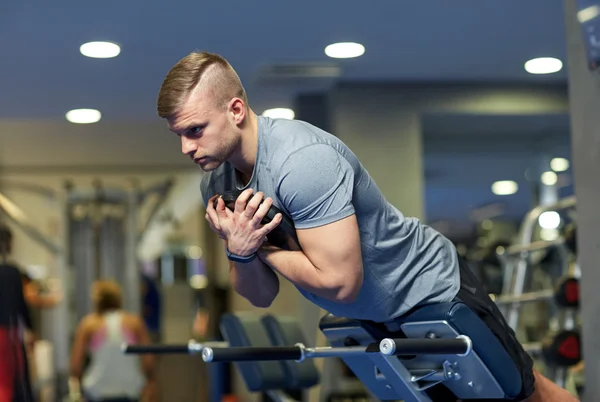 Young man flexing back muscles on bench in gym — Stock Photo, Image