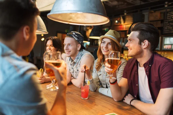 Amigos felizes com bebidas conversando no bar ou pub — Fotografia de Stock