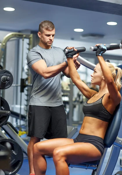 Hombres y mujeres flexionando los músculos en la máquina de gimnasio — Foto de Stock