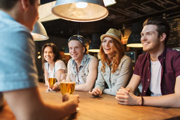 Счастливые друзья пьют пиво и разговаривают в баре — стоковое фото