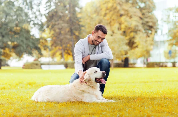 Uomo felice con cane labrador nel parco cittadino autunnale — Foto Stock