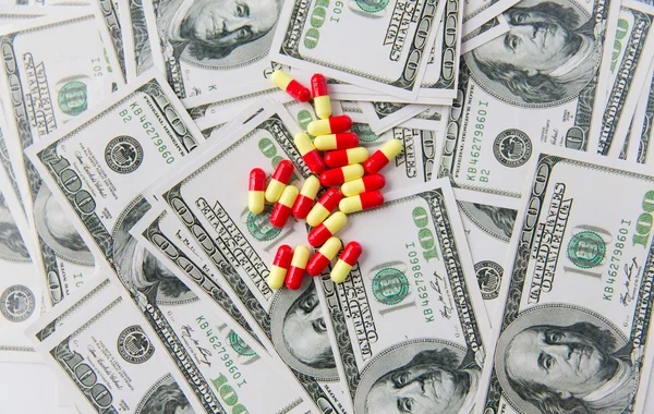 Pastillas médicas o drogas y dinero en efectivo en dólares — Foto de Stock
