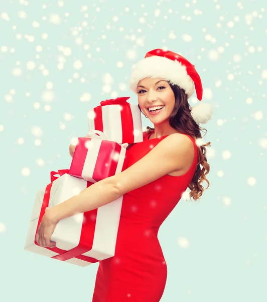 Vrouw in helper kerstmuts met vele geschenkdozen — Stockfoto
