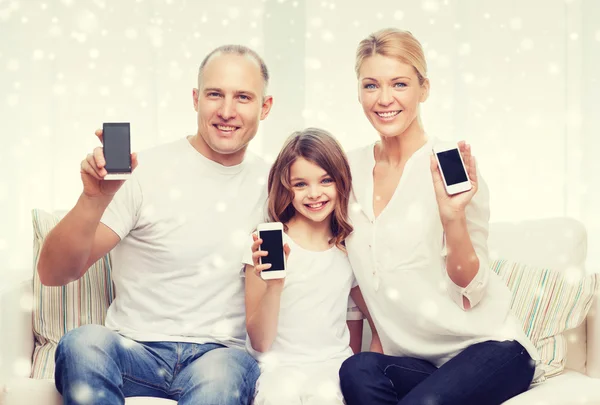 Família feliz mostrando smartphones telas em branco — Fotografia de Stock