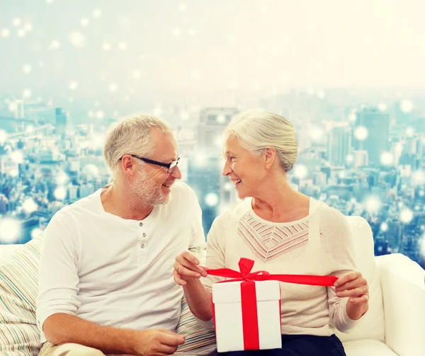 Feliz pareja de ancianos con caja de regalo en casa — Foto de Stock