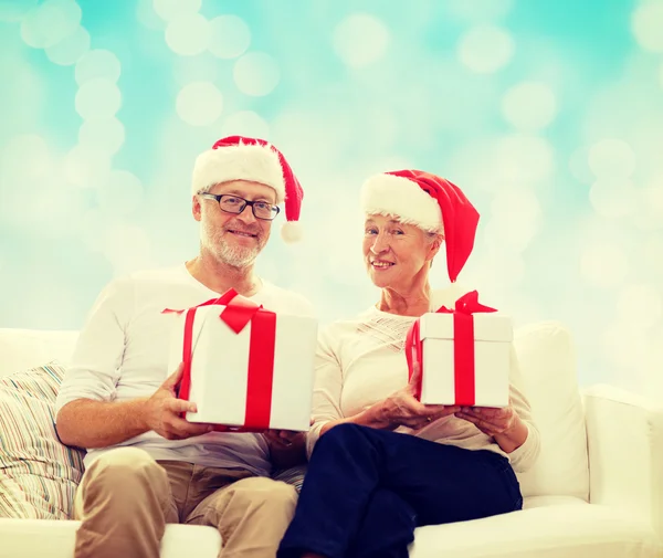Glad äldre par i santa hattar med presentförpackning — Stockfoto