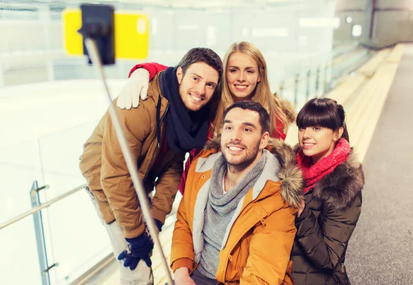 Amigos felizes com smartphone na pista de patinação — Fotografia de Stock