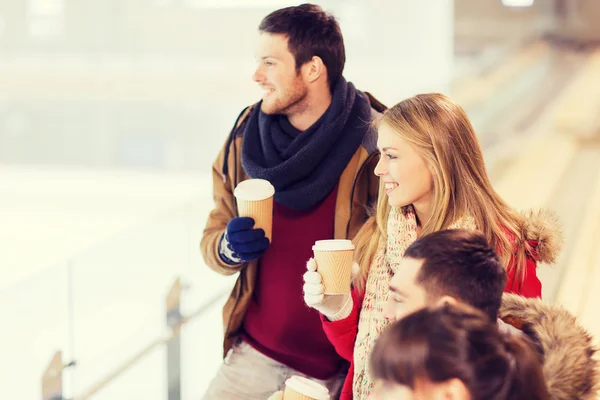 Happy friends with coffee cups on skating rink — Stock Photo, Image