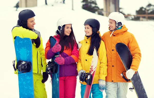 Happy friends in helmets with snowboards talking — Stock Photo, Image