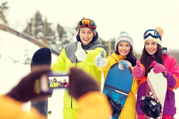 Amigos felices con tablas de snowboard y smartphone —  Fotos de Stock