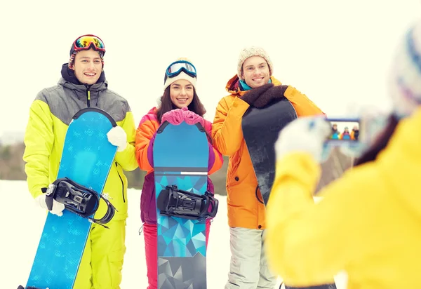 Amigos felices con tablas de snowboard y smartphone —  Fotos de Stock