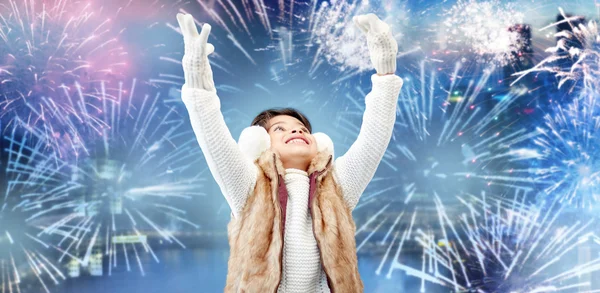 Glückliches kleines Mädchen mit Ohrenschützern über Feuerwerk — Stockfoto