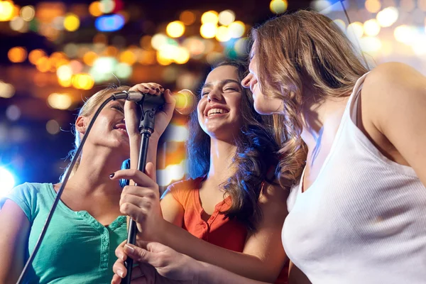 Felizes jovens mulheres cantando karaoke no clube noturno — Fotografia de Stock