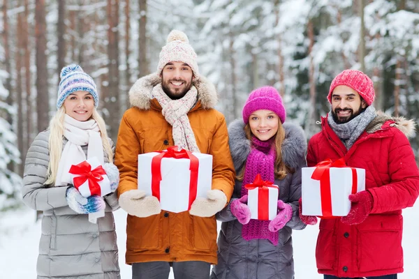 Gelukkige vrienden met gift boxes in winter forest — Stockfoto