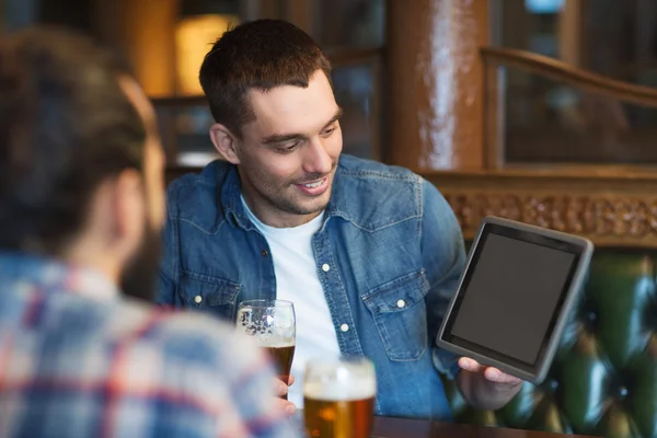 Друзья мужчины с планшетным ПК пьют пиво в баре — стоковое фото