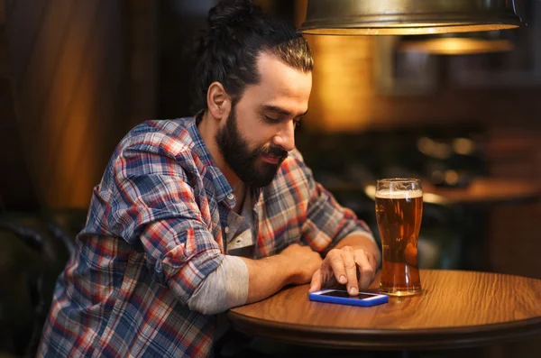 Человек со смартфоном и пивом в баре — стоковое фото