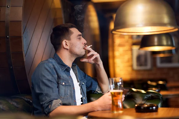 Hombre beber cerveza y fumar cigarrillo en el bar — Foto de Stock