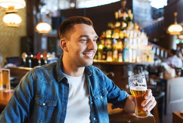 Szczęśliwy człowiek pije piwo w barze lub pubie — Zdjęcie stockowe