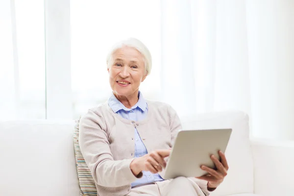 Mulher sênior feliz com tablet pc em casa — Fotografia de Stock