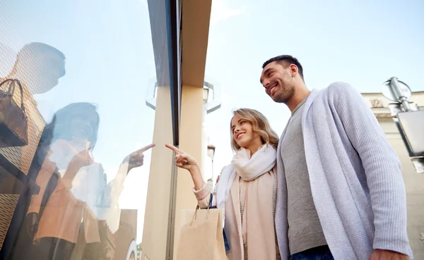 Feliz pareja con bolsas de compras en el escaparate — Foto de Stock